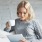 Lifestyle image of a woman reading on her iPad and drinking coffee