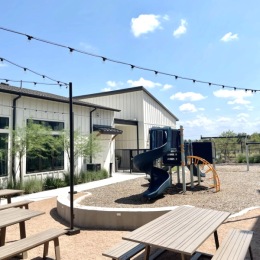 Outdoor playground with slide and picnic tables at Citizen House Blue Bluff apartments in East Austin, TX.